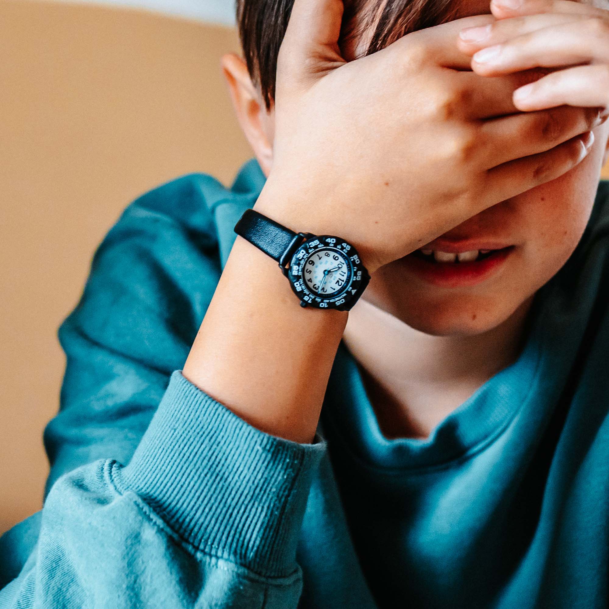 Junge, der eine schwarze Uhr mit weißem ziffernblatt trägt